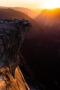 Sunlit granite cliff with a couple standing on the summit overlook