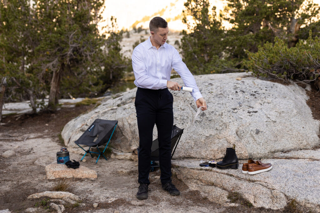 Groom fastening his shirt cuff at a rocky campsite