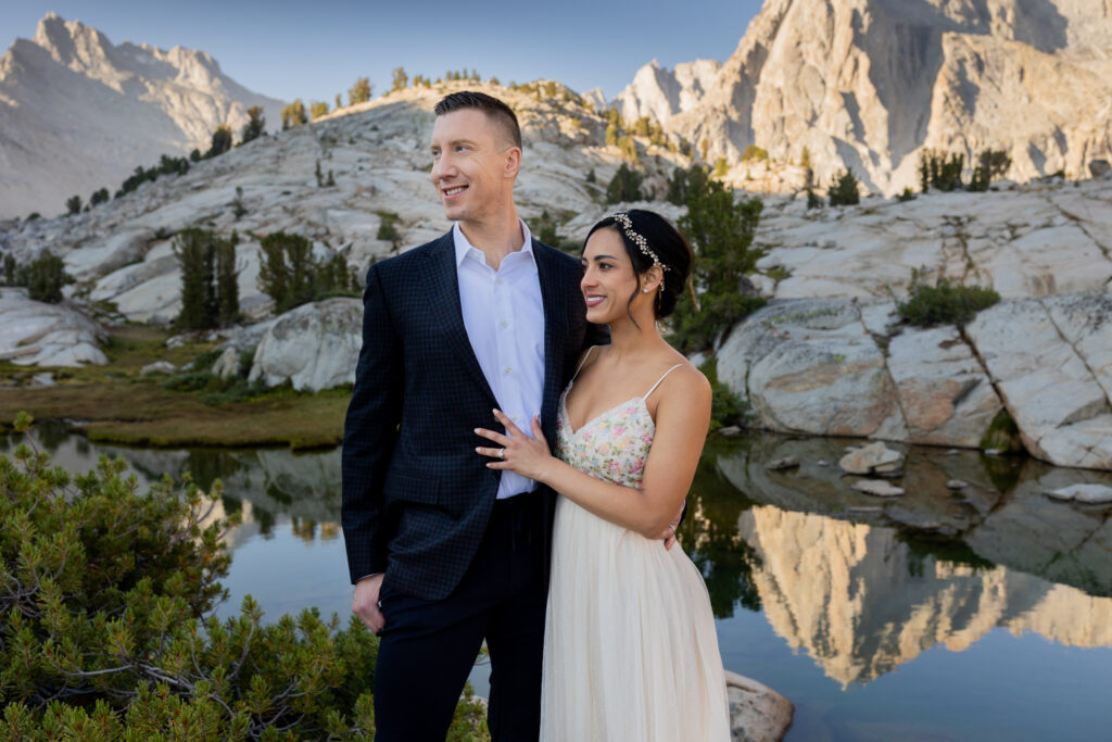 Couple posing together beside a still mountain lake