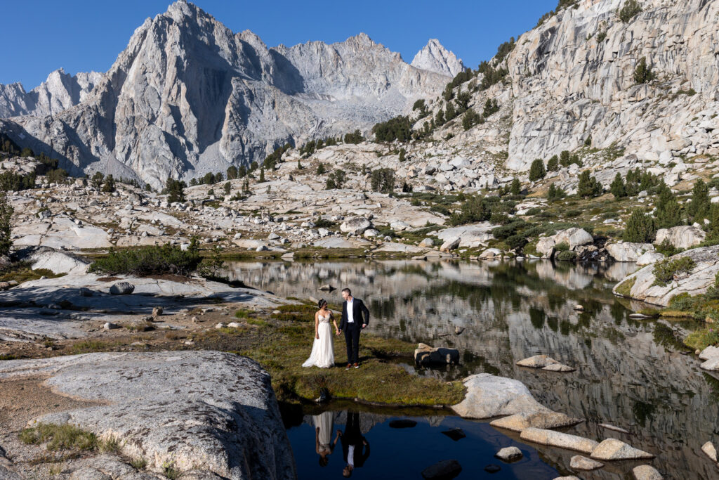 Wedding couple reflected in a still alpine lake