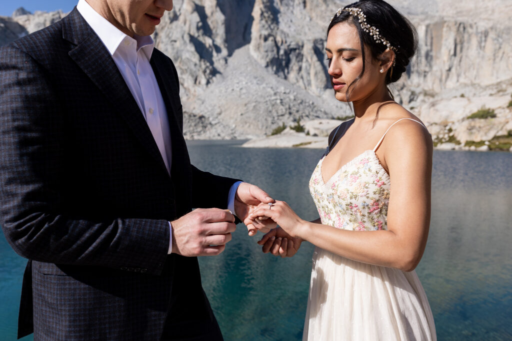 Close-up of the couple exchanging rings beside the lake