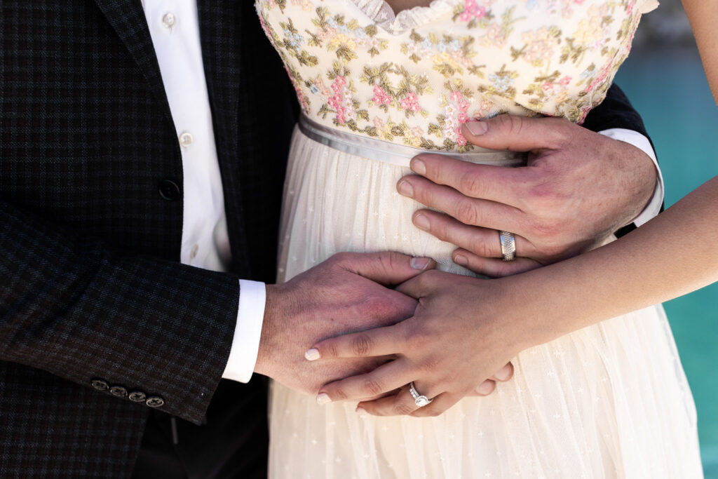 Close-up of newlyweds holding hands and showing their wedding rings