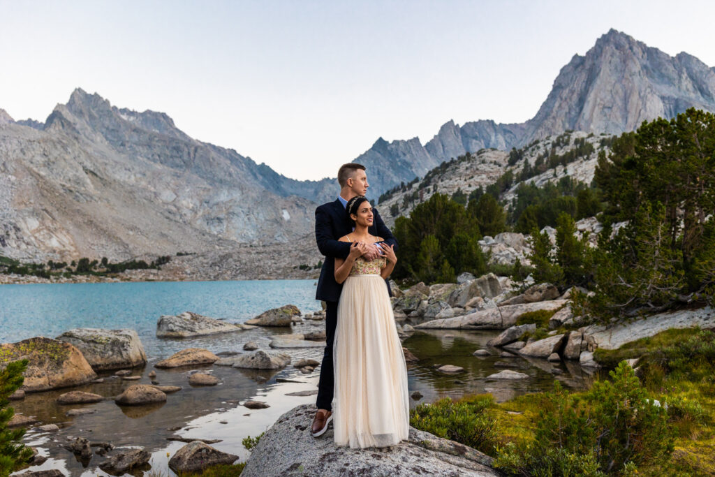 Groom embracing the bride beside an alpine lake